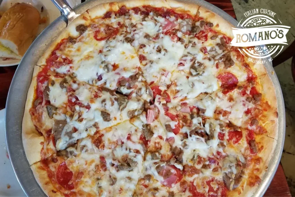 Fresh pizza topped with cheese, olives, tomatoes, and peppers.